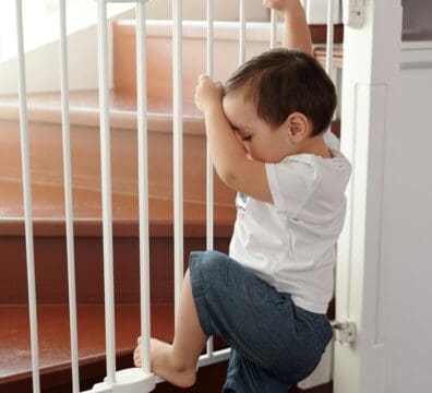 a baby trying to climb on the secured baby gates